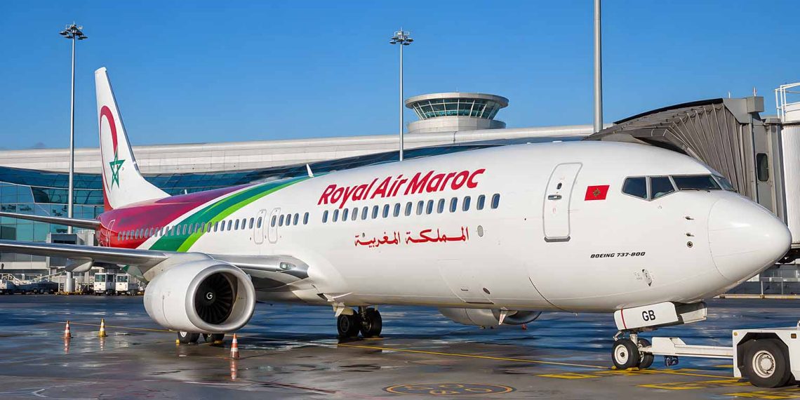 J'ai pris Royal Air Maroc pour la première fois : retour d'expérience (Avis complet 2026) 1 Avion de la compagnie Royal Air Maroc stationné à la porte d'embarquement d'un terminal aéroportuaire sous un ciel bleu.