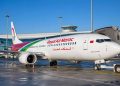 Avion de la compagnie Royal Air Maroc stationné à la porte d'embarquement d'un terminal aéroportuaire sous un ciel bleu.