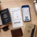 Ma checklist avant chaque voyage (je ne l'oublie jamais) 3 Checklist voyage avec passeport, billet d'avion papier, smartphone et accessoires de voyage disposés sur un bureau en bois.