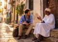 Journaliste de voyage discutant avec un habitant swahili sur un banc traditionnel à Stone Town, Zanzibar.