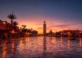 Vue panoramique de la place Jemaa el-Fna vide au lever du soleil à Marrakech avec le minaret de la Koutoubia en arrière-plan.