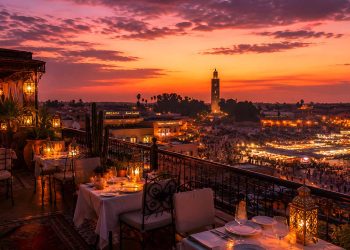 Vue panoramique depuis la terrasse d'un restaurant rooftop à Marrakech au coucher du soleil sur la médina.
