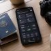 Les 12 applications que j'utilise à chaque voyage (Guide 2026) 3 Sélection des meilleures applications de voyage indispensables sur un smartphone posé sur une table aux côtés d'un passeport.