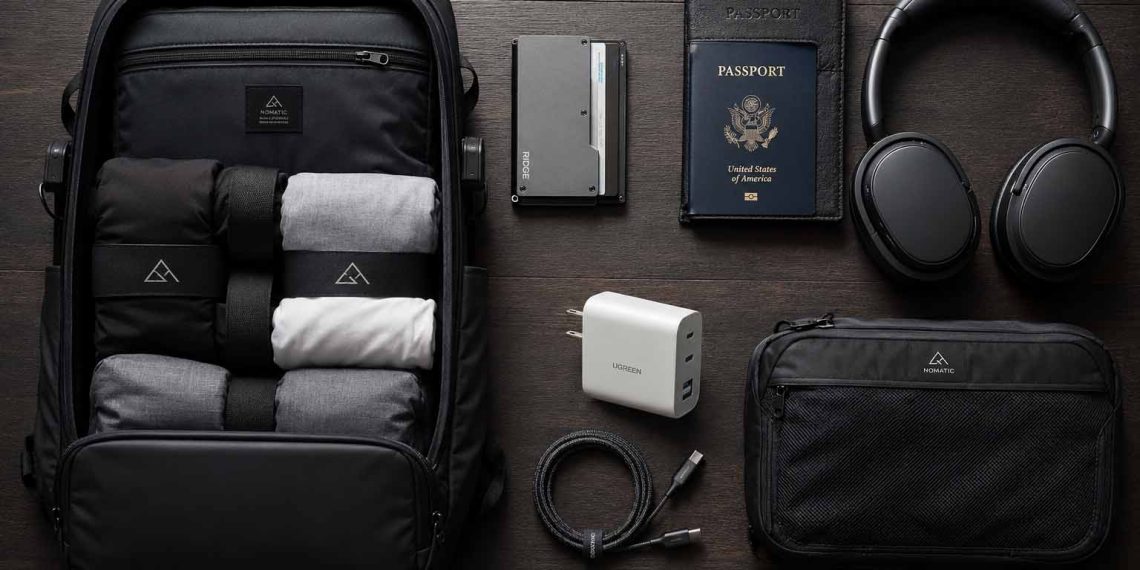 Les accessoires de voyage que j'utilise vraiment (Guide complet 2026) 1 Flat lay artistique des meilleurs accessoires de voyage minimalistes et techniques de 2026 disposés sur une table en bois sombre.