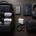 Les accessoires de voyage que j'utilise vraiment (Guide complet 2026) 4 Flat lay artistique des meilleurs accessoires de voyage minimalistes et techniques de 2026 disposés sur une table en bois sombre.