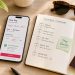 Bureau de voyageur avec smartphone affichant une réservation d'hôtel flexible avec annulation gratuite et carnet de voyage.