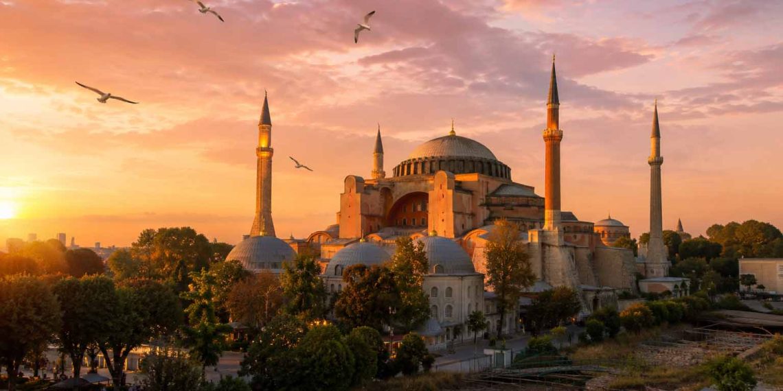 Mon séjour à Istanbul : les pièges que j'ai évités (Guide pratique, budget et conseils 2026) 1 Vue panoramique de la mosquée Sainte-Sophie à Istanbul au lever du soleil avec des mouettes dans le ciel doré.
