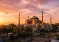 Vue panoramique de la mosquée Sainte-Sophie à Istanbul au lever du soleil avec des mouettes dans le ciel doré.
