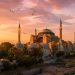 Mon séjour à Istanbul : les pièges que j'ai évités (Guide pratique, budget et conseils 2026) 3 Vue panoramique de la mosquée Sainte-Sophie à Istanbul au lever du soleil avec des mouettes dans le ciel doré.