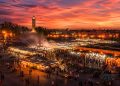 Vue panoramique de la place Jemaa el-Fna à Marrakech au coucher du soleil avec les stands de nourriture fumants et la mosquée Koutoubia.