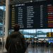 Mon vol a été annulé : comment j'ai obtenu un remboursement (Guide 2026) 6 Un voyageur inquiet devant un panneau d'affichage des vols d'un aéroport indiquant un vol annulé en rouge.