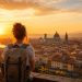 Mes 15 destinations préférées à moins de 500 € 4 Voyageur sac au dos contemplant une ville historique européenne au lever du soleil pour un voyage pas cher sous la barre des 500 euros.