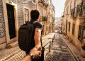 Voyageur portant un unique sac à dos technique de voyage dans une rue pavée historique d'une ville européenne.