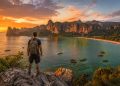 Voyageur solo contemplant le coucher de soleil sur les falaises de Railay Beach en Thaïlande.
