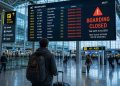 Un voyageur dépité de dos regardant un panneau d'affichage des vols indiquant l'embarquement clos dans un grand aéroport moderne en 2026.