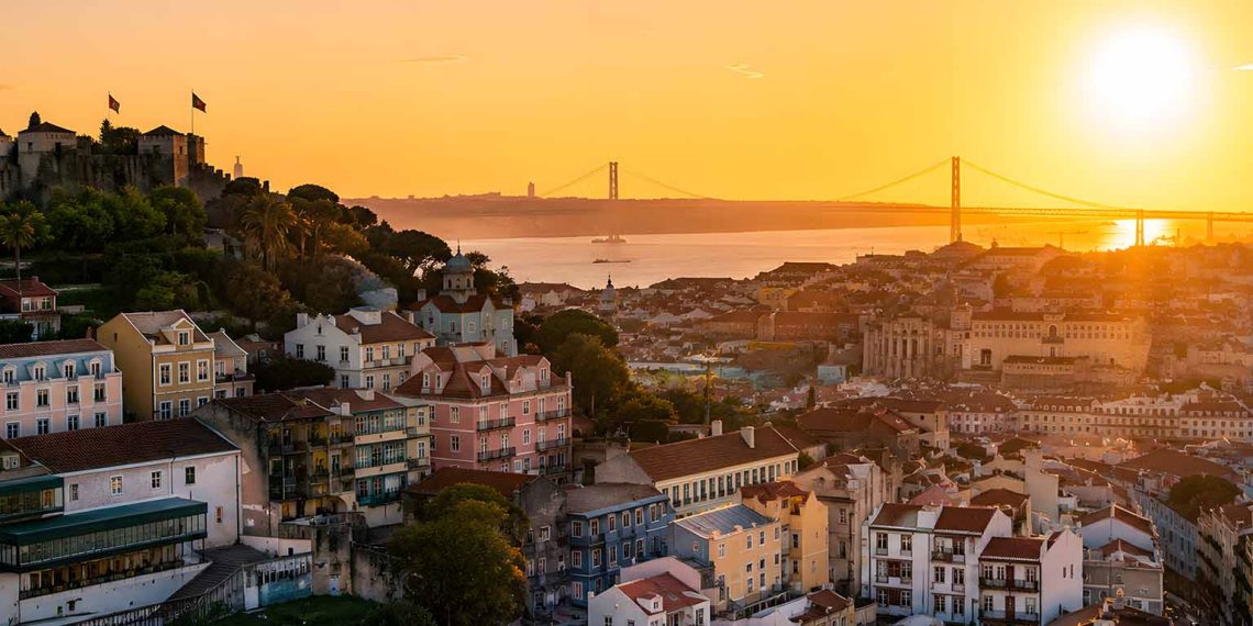 Mon week-end à Lisbonne : budget, hôtels et erreurs à éviter (Guide complet 2026) 1 Vue d'ensemble panoramique sur les toits de Lisbonne au lever du soleil avec le Tage en arrière-plan.