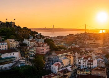 Vue d'ensemble panoramique sur les toits de Lisbonne au lever du soleil avec le Tage en arrière-plan.