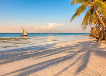 J'ai découvert Zanzibar hors des circuits touristiques : les endroits secrets qui m'ont le plus marqué (Guide 2026) 8 Plage déserte de Zanzibar à marée basse avec un dhow traditionnel au lever du soleil, illustration du voyage hors des sentiers battus.